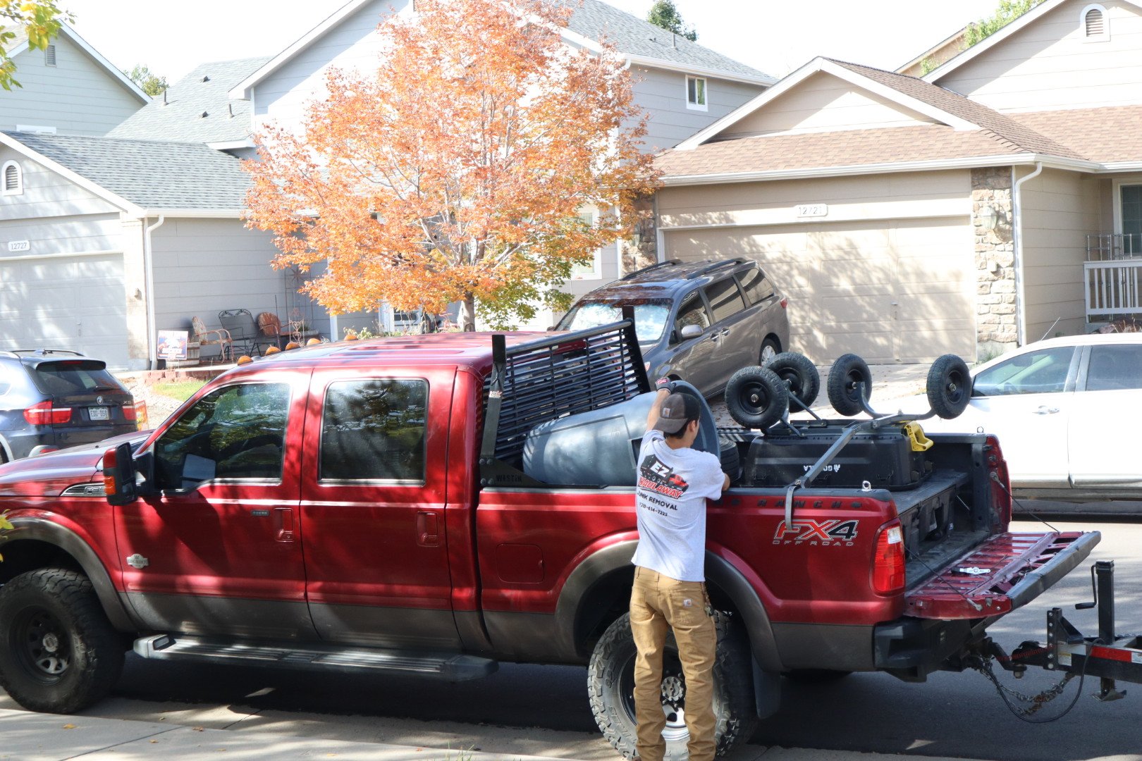 EZ Haulaway crew loading the maroon pickup beside the black dump trailer