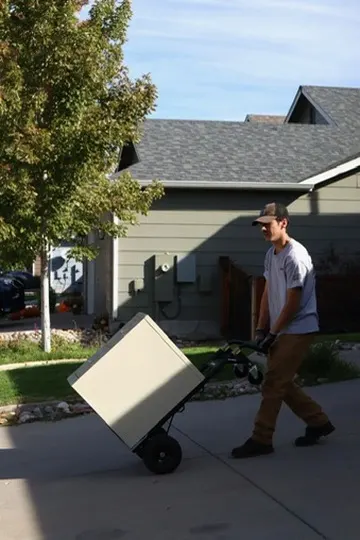 Ben wheeling a cabinet down a Parker driveway on a dolly