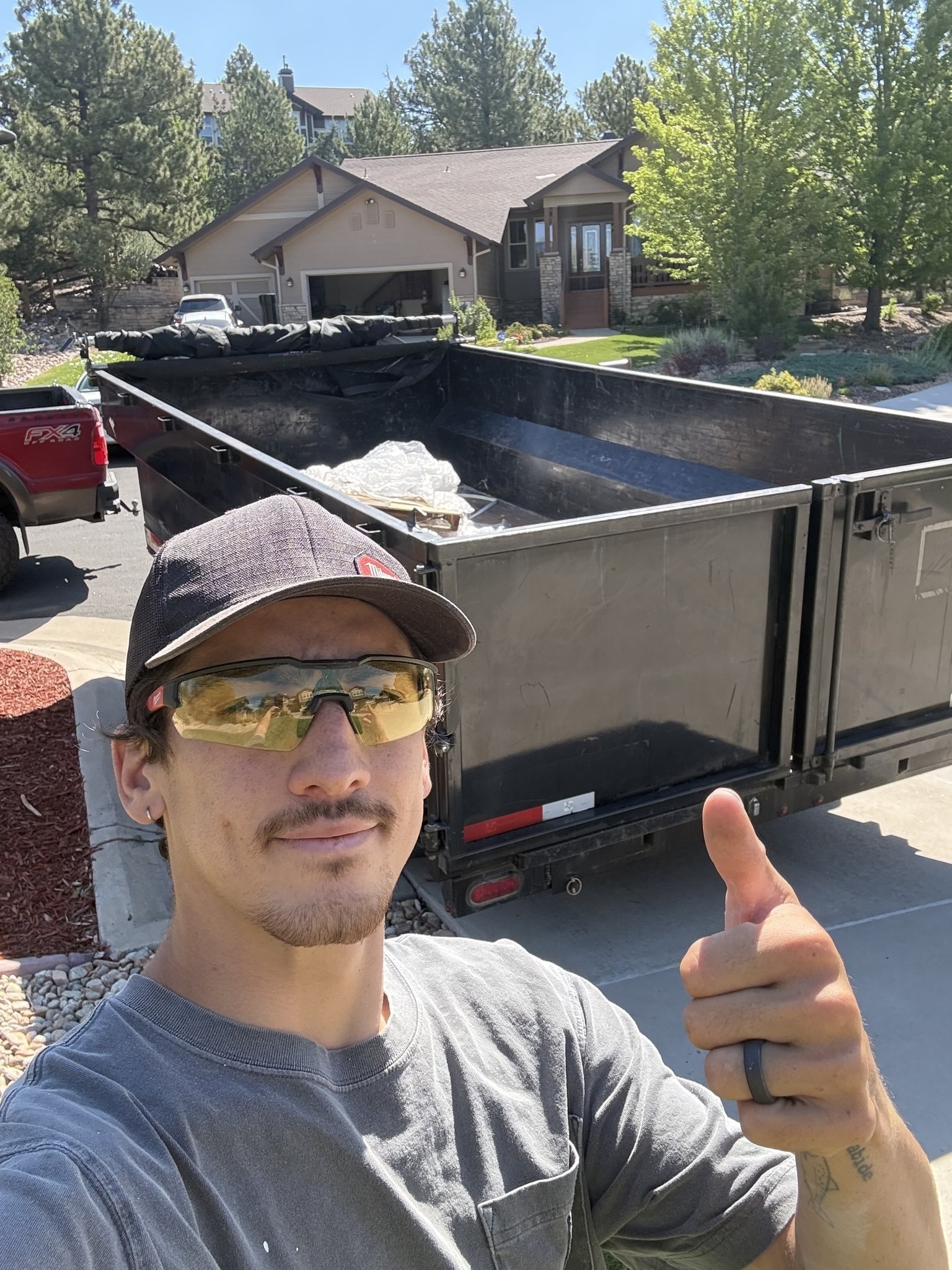 Ben from EZ Haulaway giving a thumbs up in front of the dump trailer at a jobsite